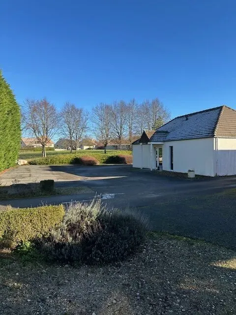 âtiment blanc de l'agence avec son parking privé bordé d'espaces verts.